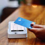 a-person-holding-a-credit-card-in-front-of-a-machine