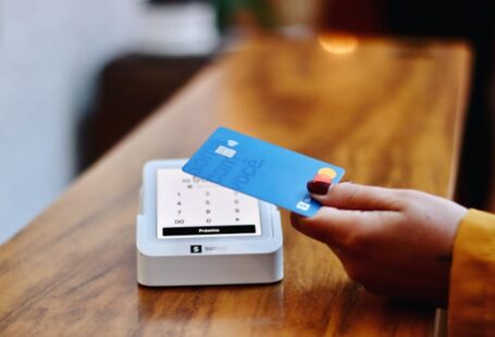 a-person-holding-a-credit-card-in-front-of-a-machine