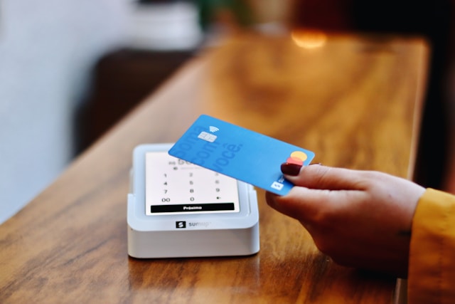 a-person-holding-a-credit-card-in-front-of-a-machine