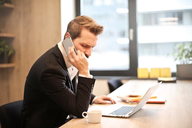 man-having-a-phone-call-in-front-of-a-laptop