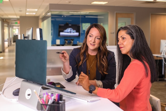two-women-sitting-at-a-table-looking-at-a-computer-screen